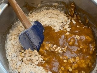 Mixing browned butter and sugar into oat and flour mixture.